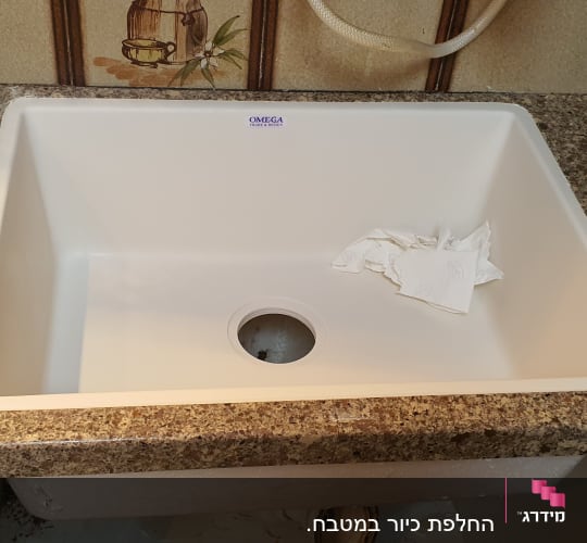 התקנת כיור מטבח לבן בתוך משטח שיש במהלך העבודה